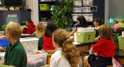 Einige Grundschulkinder sitzen in einer Schulklasse und hören zu.