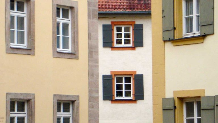 Ansicht von drei Häuserfassaden mit Wohnungen, die teils unbewohnt ausschauen.