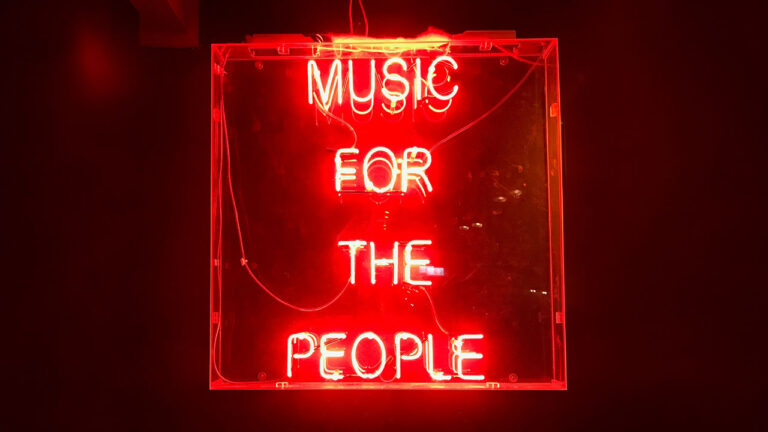 Rotes Neonschild mit der Aufschrift „Music for the people“.