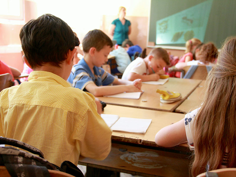 Kinder sitzen in einer Schulklasse und arbeiten.